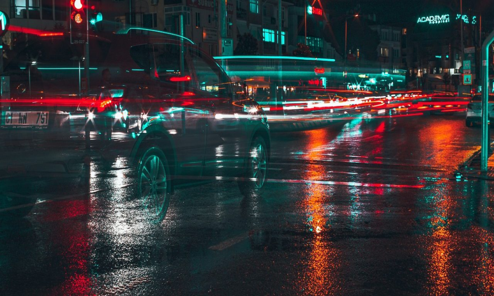 Moody image of a nighttime street with passing vehicles